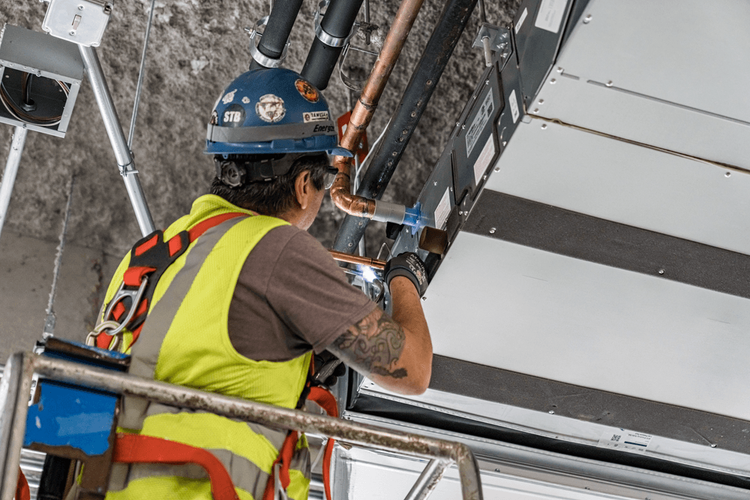 contractor with yellow vest and blue hard hat installing electric system