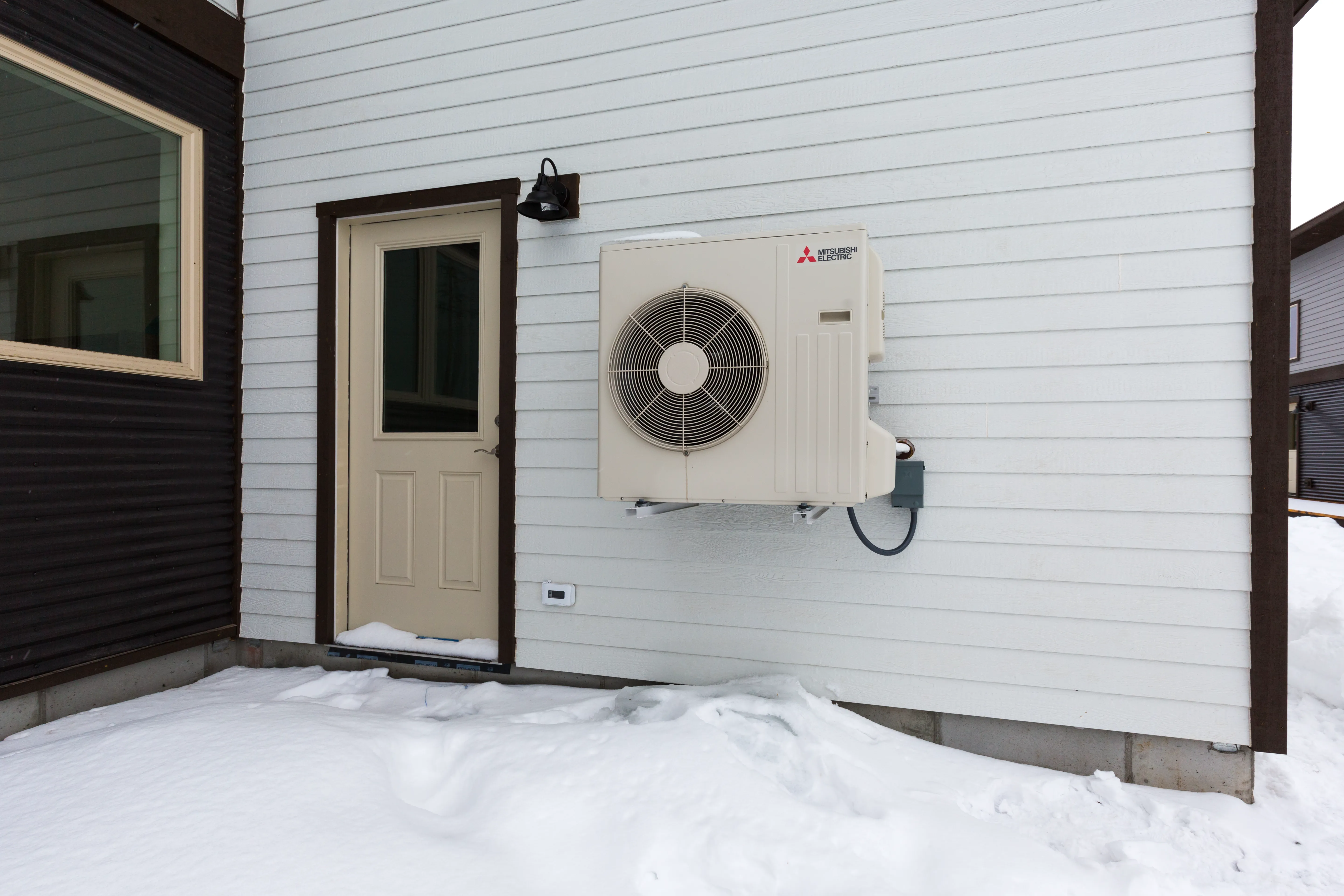 Outdoor heat pump in Cloverleaf Court house in deep snow